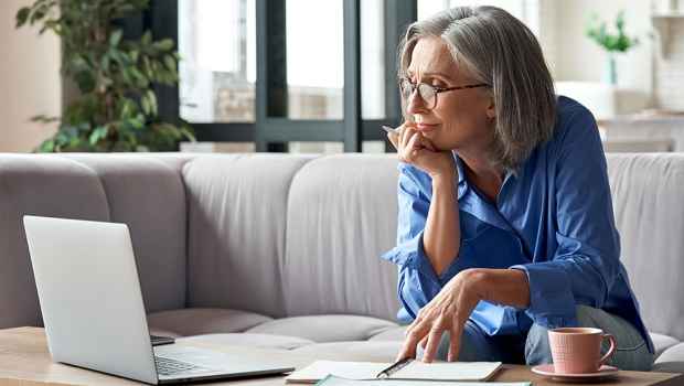 Woman on couch watches laptop screen